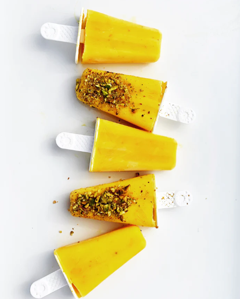 Saffron lassi popsicles bright yellow frozen treat to make at home topped with pistachios optionally